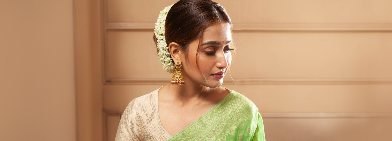 A picture of a woman wearing Indian earrings with a saree.