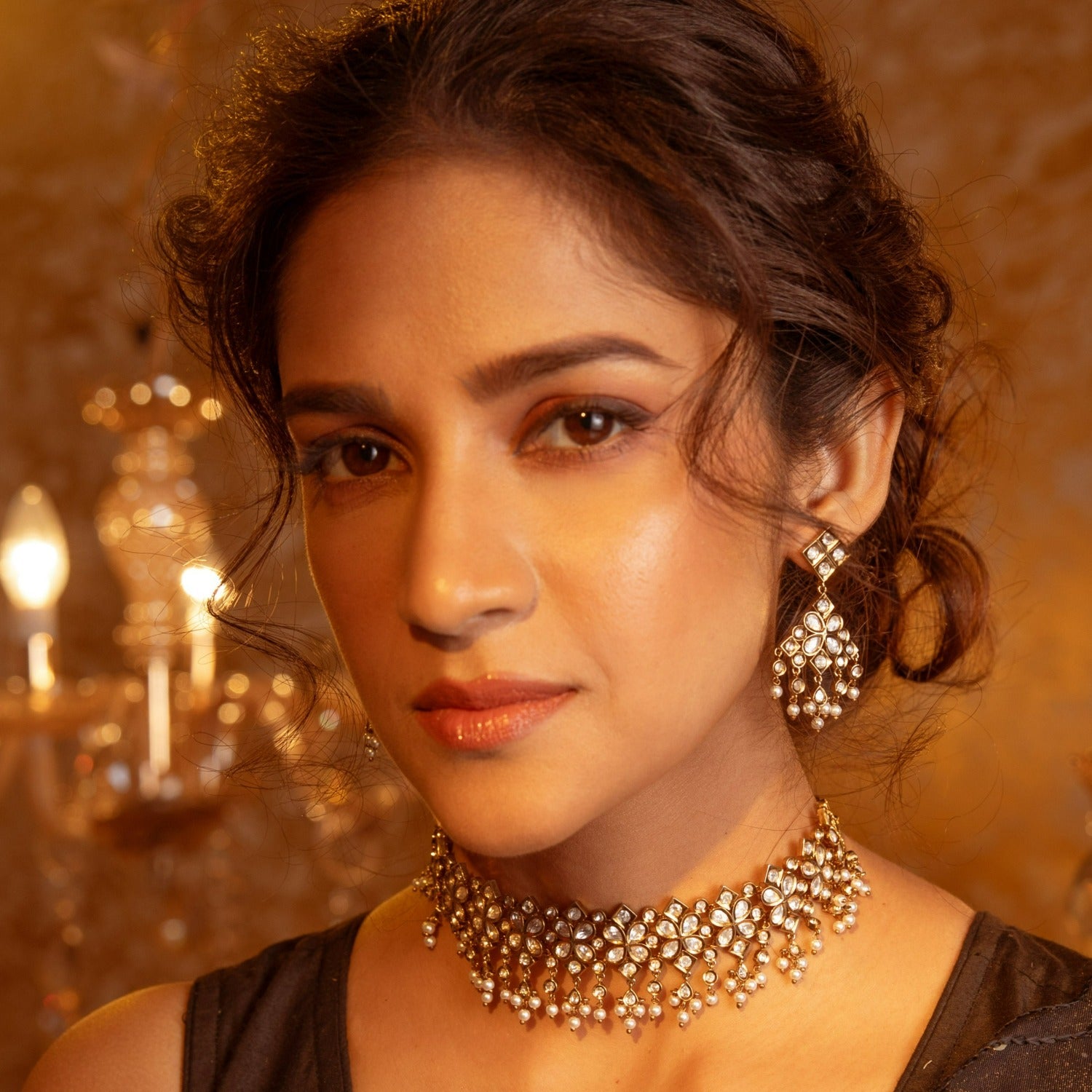A picture of an Indian artificial jewelry set with a gold-toned choker necklace and matching earrings with Cubic Zirconia stones.