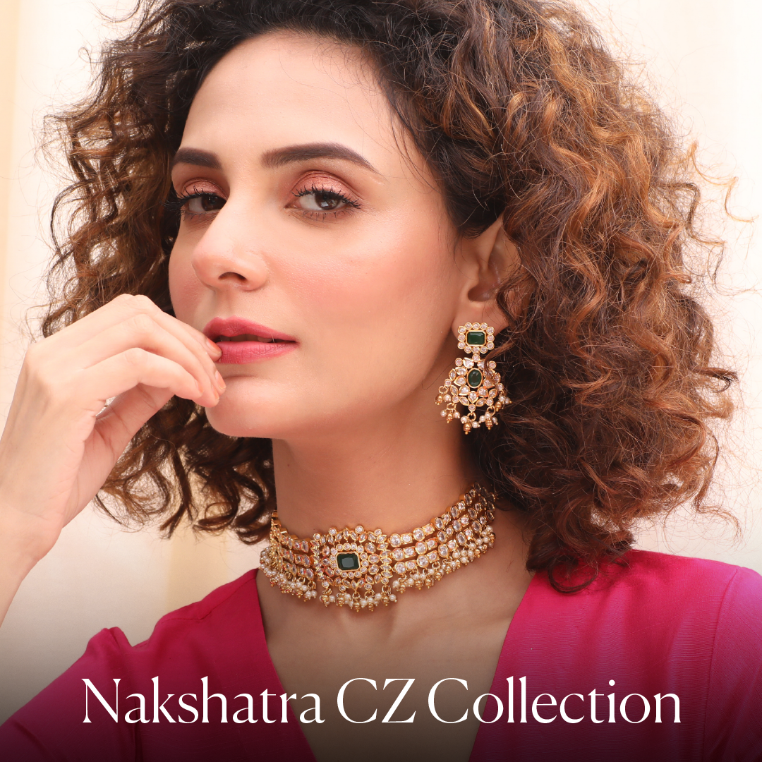 A woman with curly hair wearing a CZ/American Diamonds studded choker and earrings with green stone at at the centre