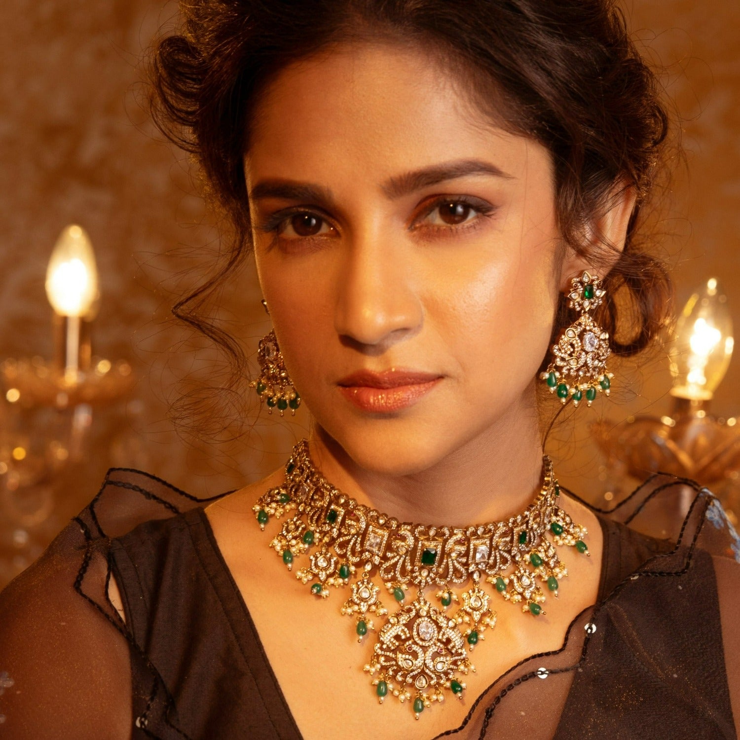 An image of Indian artificial jewelry. It is an antique gold plated short necklace with matching earrings set, featuring green gemstones and Cubic Zirconia.