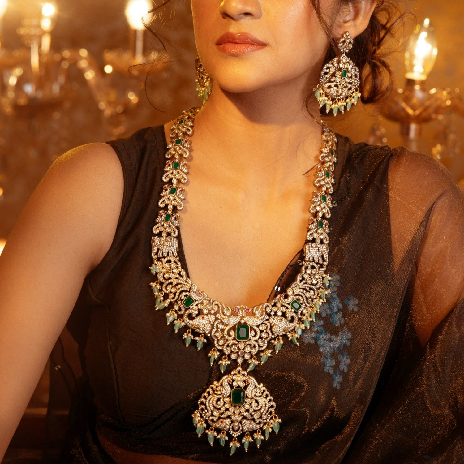 A picture of an Indian artificial jewelry set: a Victorian plated necklace and earrings with green gemstones and Cubic Zirconia.