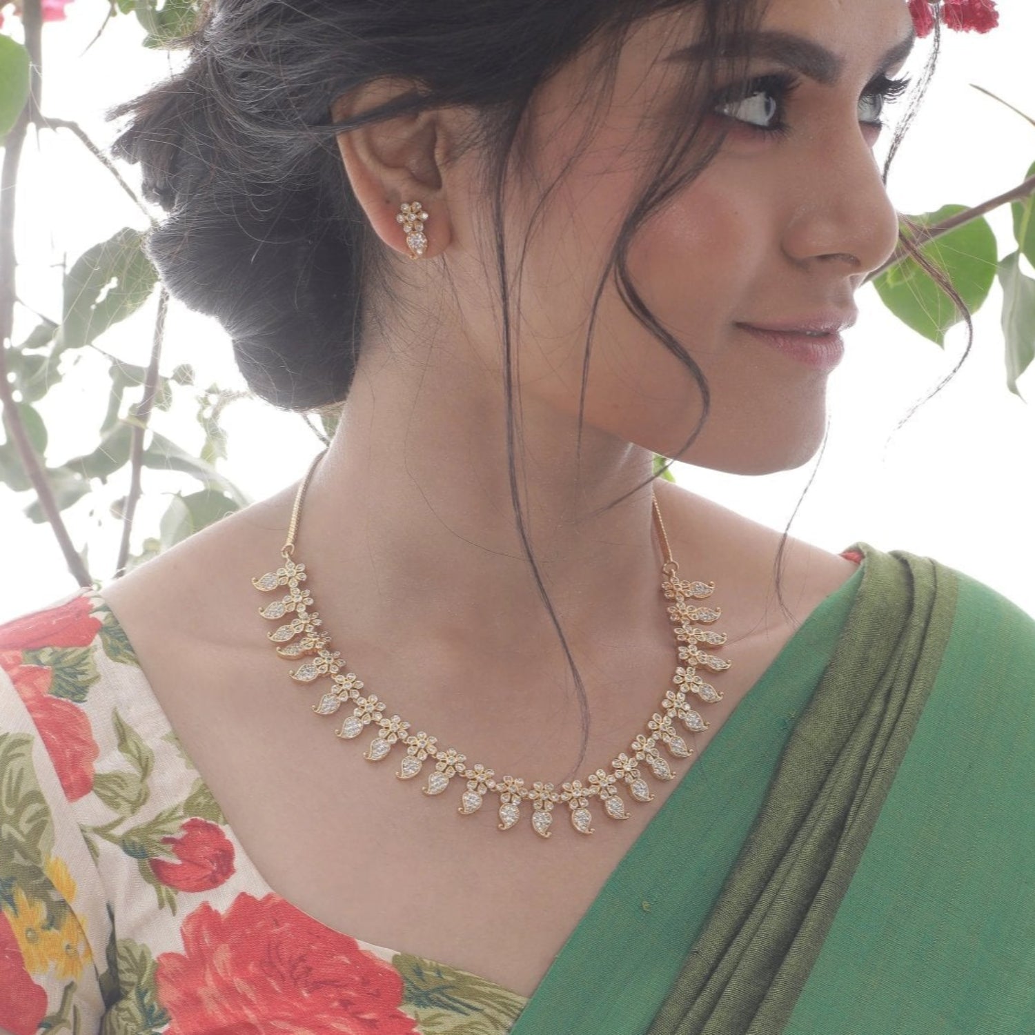 A picture of an Indian artificial jewelry set: a gold-plated necklace and earrings featuring teardrop-shaped red gemstones with Cubic Zirconia on a white background. 