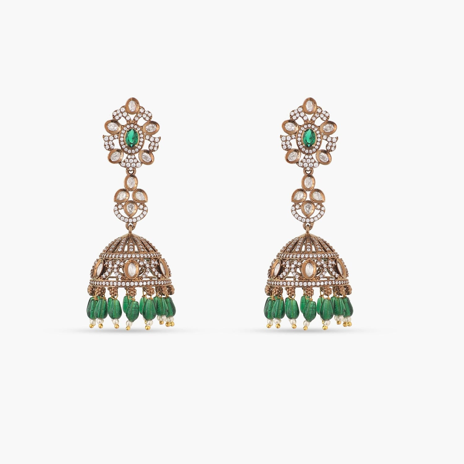A picture of a pair of Indian artificial jhumka earrings with green gemstones and Cubic Zirconia stones on a white surface.