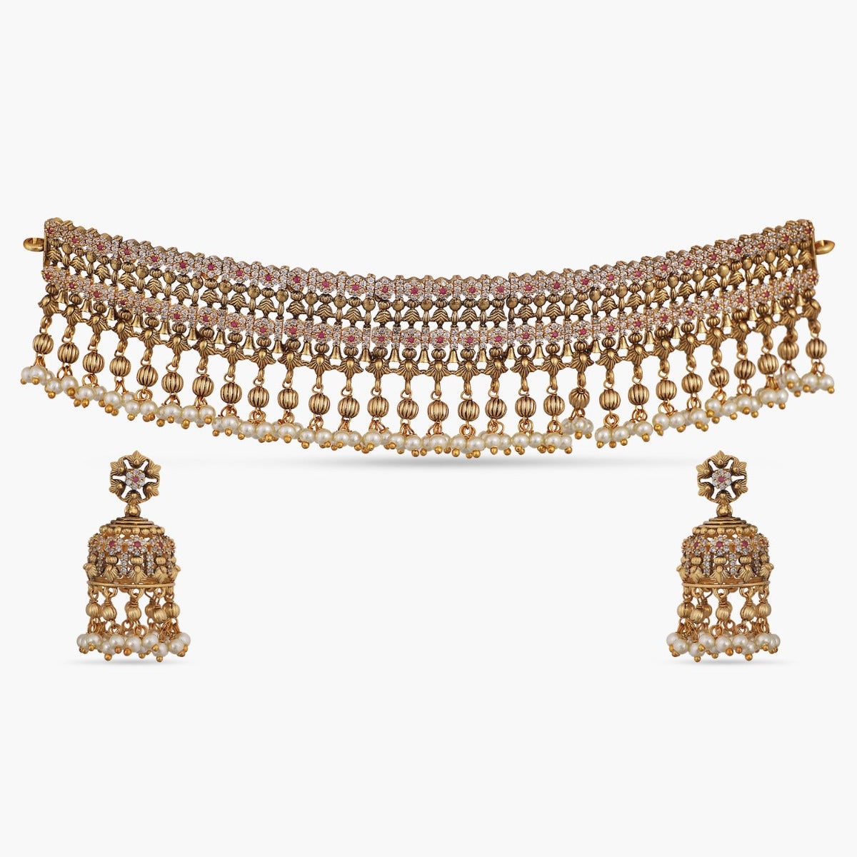 A picture of an Indian artificial jewelry set: an antique gold-plated choker and earrings with pearls and small red gemstones, Cubic Zirconia.