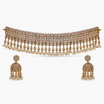 A picture of an Indian artificial jewelry set: an antique gold-plated choker and earrings with pearls and small red gemstones, Cubic Zirconia.