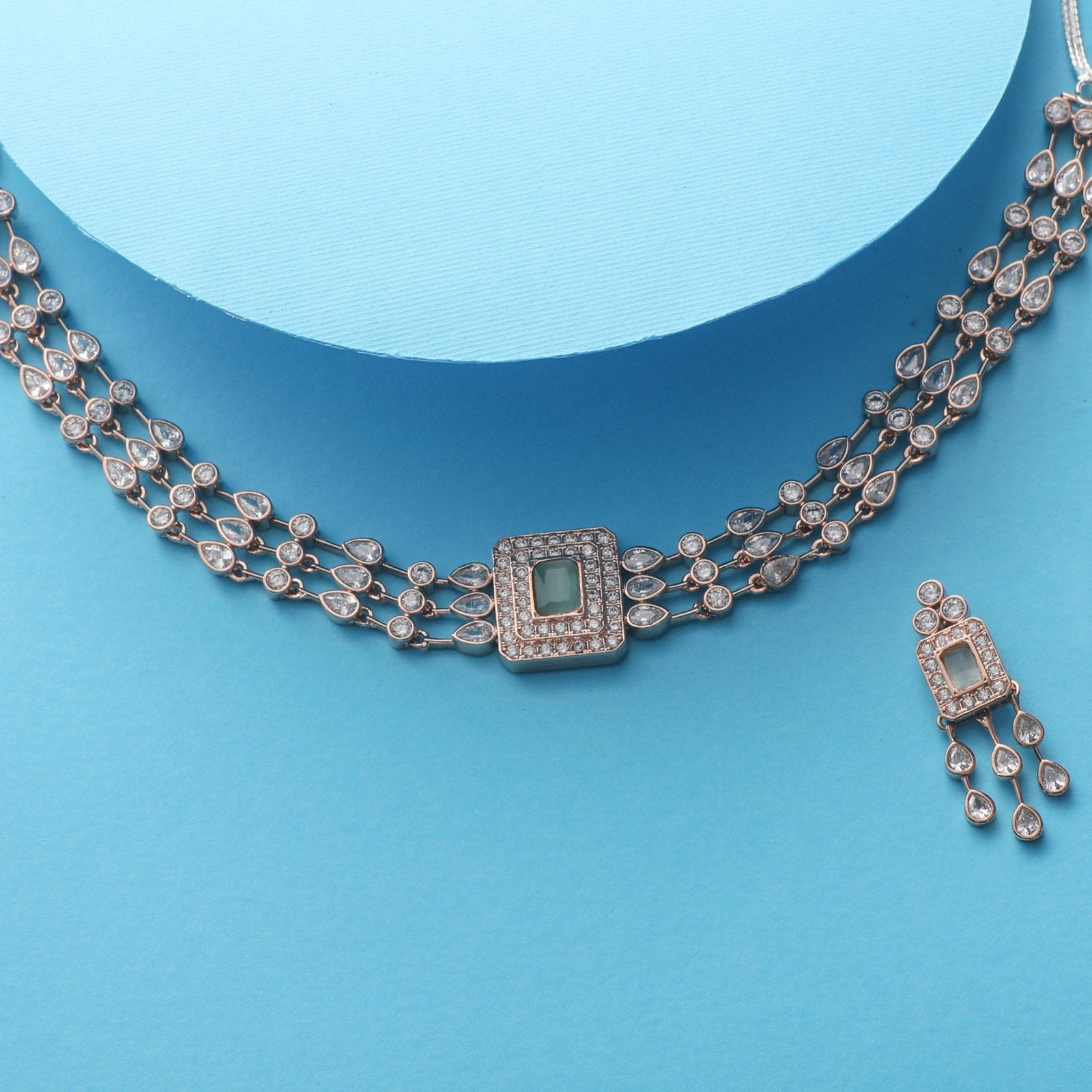 A picture of Indian artificial jewelry. It is a choker necklace and matching earrings set with Cubic Zirconia and red gemstones on a white background.
