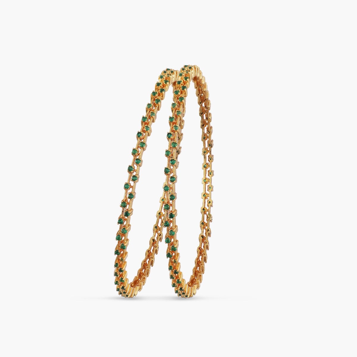 A close-up image of a pair of gold plated bangles with green gemstones on a white background.