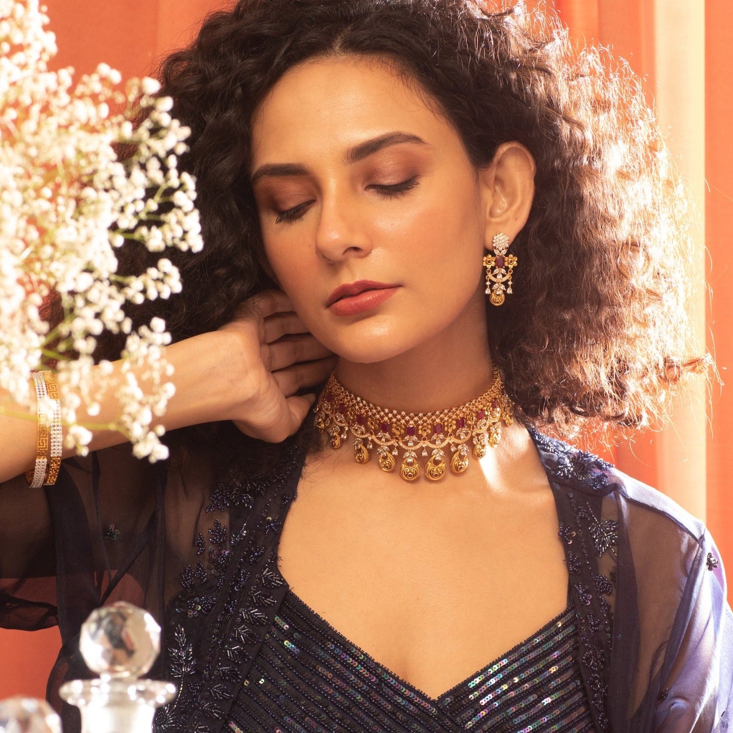 A picture of an Indian artificial gold plated choker necklace with green gemstones and Cubic Zirconia on a white background.